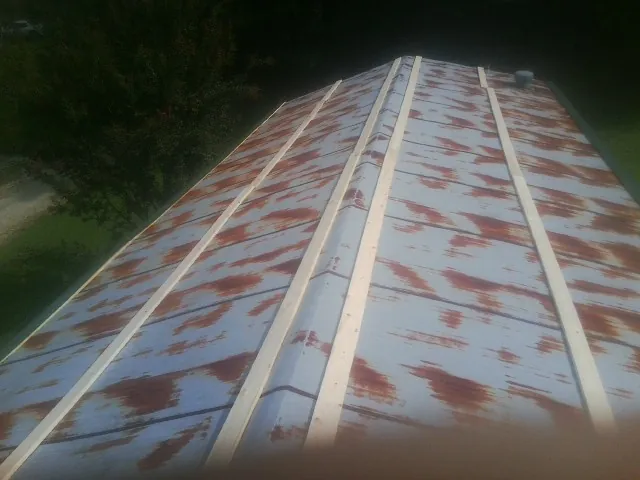 Rusted metal roof panels with new wood purlins before replacement — Storm Damage Roof Repair in Grant by Roofing Brothers