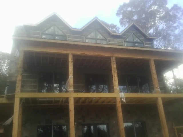 Dormers and porch framing on a large log home under construction — Roof Coating work by our crew in Grant
