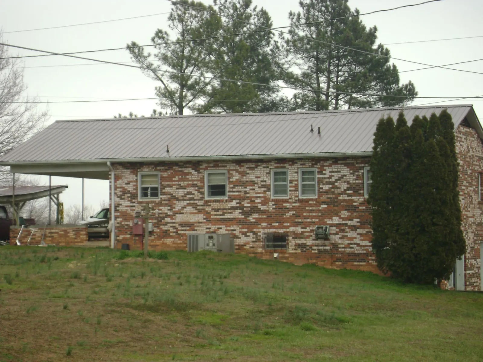 Gray metal roof on a brick split level home with a carport in Grant